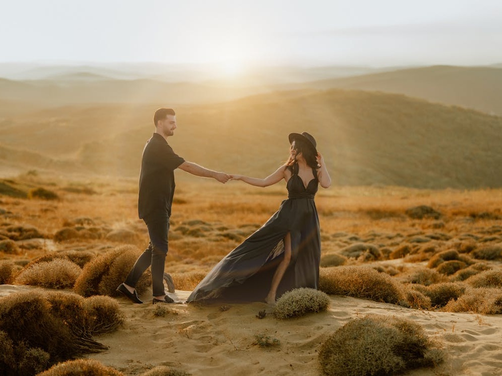 Casal caminhando de mãos dadas ao pôr do sol